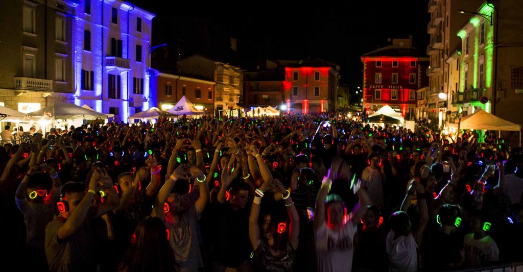 Platz bei Nacht voller Menschen mit Silent Disco Kopfhörern